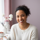 A smiling woman in a casual top, looking confidently at the camera, with a soft, blurred background.